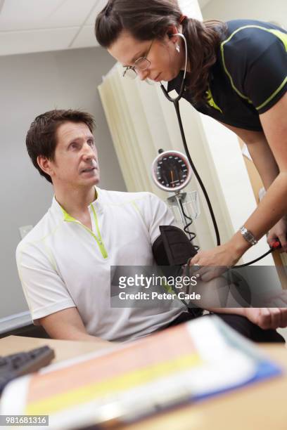 man having blood pressure checked - short sleeved stockfoto's en -beelden