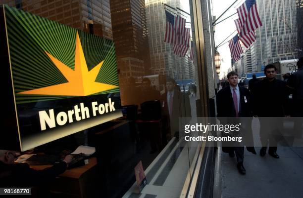 Pedestrians pass a North Fork bank branch in New York on December 16, 2003. North Fork Bancorp, the second- biggest bank on Long Island, agreed to...