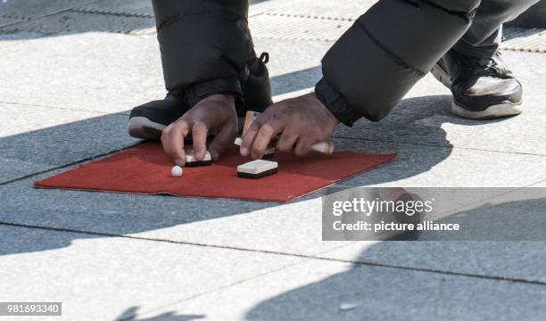 April 2018, Germany, Berlin: A shell game player at Potsdamer Platz square. Photo: Paul Zinken/dpa