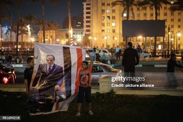 Two boys hold a poster of Egyptian President Abdel-Fattah al-Sisi during celebrations after his re-election for a second four-year term, at Tahrir...