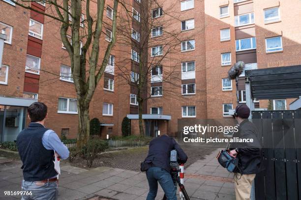 April 2018, Germany, Hannover: A cameraman in front of an apartment house in the district Gross-Buchholz, where two dead people were found. A dog...