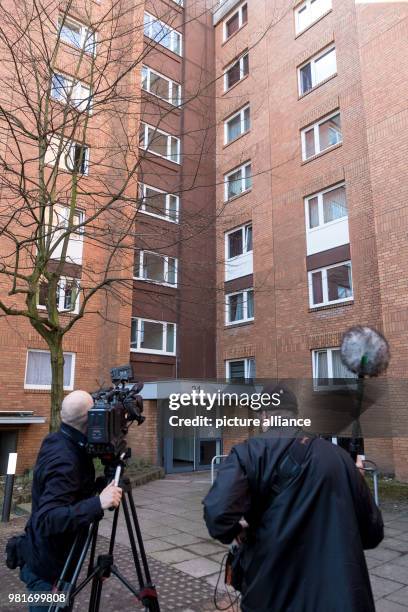 April 2018, Germany, Hannover: A cameraman in front of an apartment house in the district Gross-Buchholz, where two dead people were found. A dog...