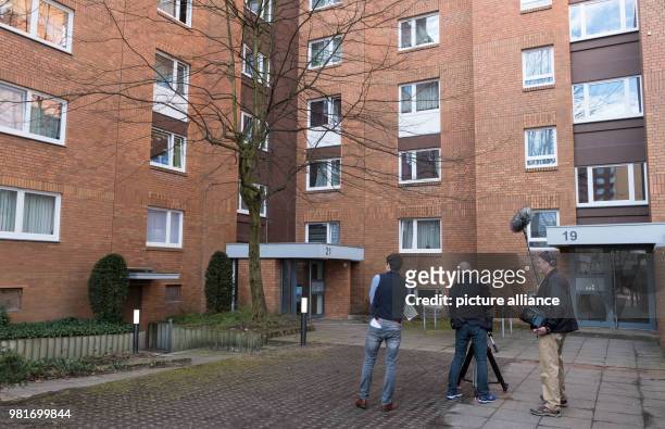 April 2018, Germany, Hannover: A cameraman in front of an apartment house in the district Gross-Buchholz, where two dead people were found. A dog...