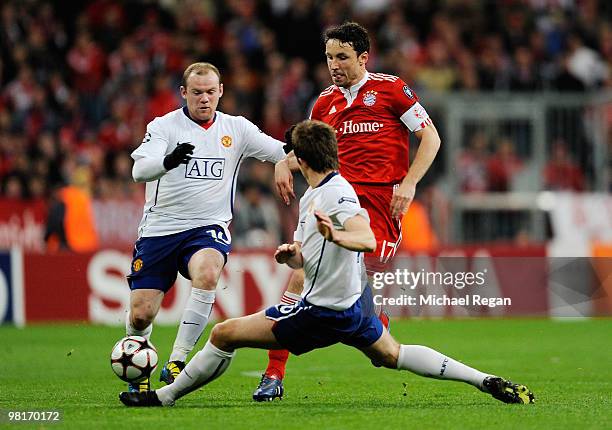 Mark Van Bommel of Bayern Muenchen is challenged by Wayne Rooney and Michael Carrick of Manchester United during the UEFA Champions League quarter...