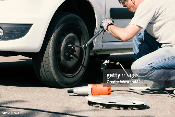 man changing car tire - tyre side view foto e immagini stock