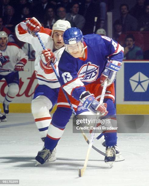 Teemu Selanne of the Winnipeg Jets skates under pressure by an opponent on the Montreal Canadiens in the early 1990's at the Montreal Forum in...