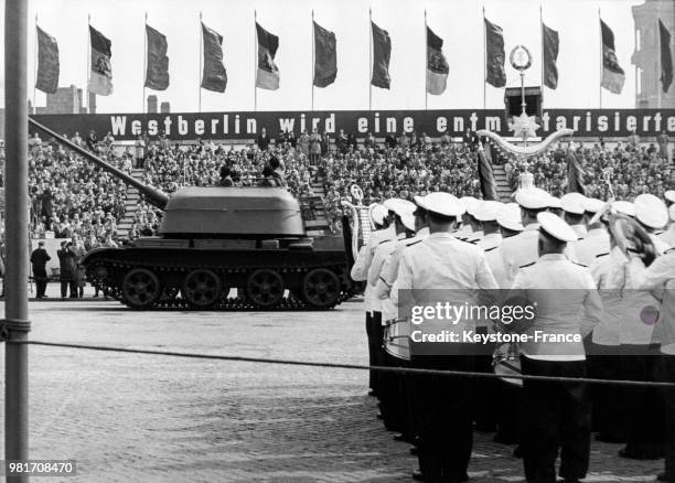 Lors d'une parade militaire le 1er mai 1960, un tank roule sur une affiche sur laquelle est inscrit 'Nous voulons un Berlin Est libre et sans...