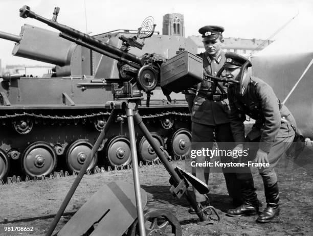 Lors d'une exposition militariste sur la Staline Allee, deux soldats inspectent des armements anti-aériens à Berlin-Est en Allemagne de l'Est, le 7...