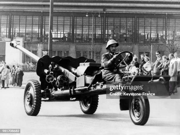 Lors de la parade militaire du 1er mai 1958 sur la place Marx-Engel à Berlin Est, en Allemagne de l'Est, un soldat montre une arme munie d'un moteur...