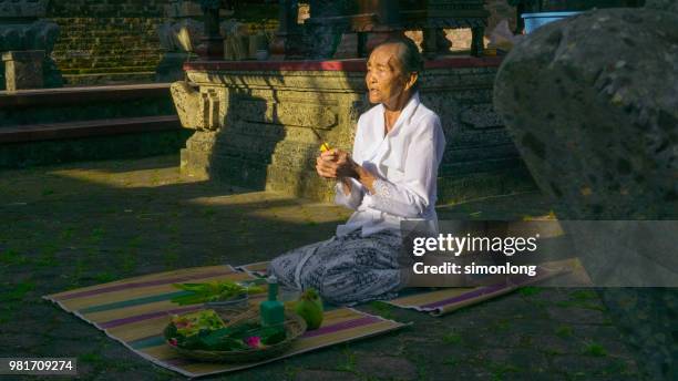 an old balinese woman praying in a temple - melasti ceremony in indonesia stock pictures, royalty-free photos & images