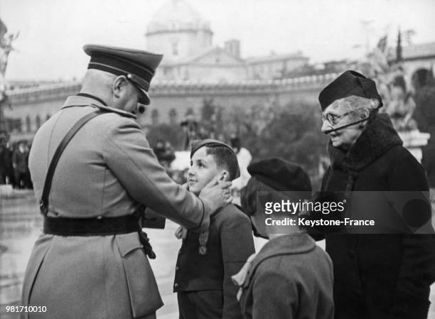 Lors d'une cérémonie, Benito Mussolini remet une décoration à un jeune balilla en Italie.