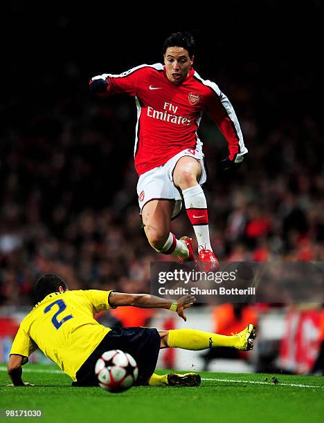 Samir Nasri of Arsenal leaps over a challenge from Daniel Alves of Barcelona during the UEFA Champions League quarter final first leg match between...