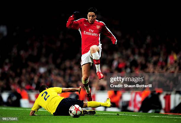 Samir Nasri of Arsenal leaps over a challenge from Daniel Alves of Barcelona during the UEFA Champions League quarter final first leg match between...