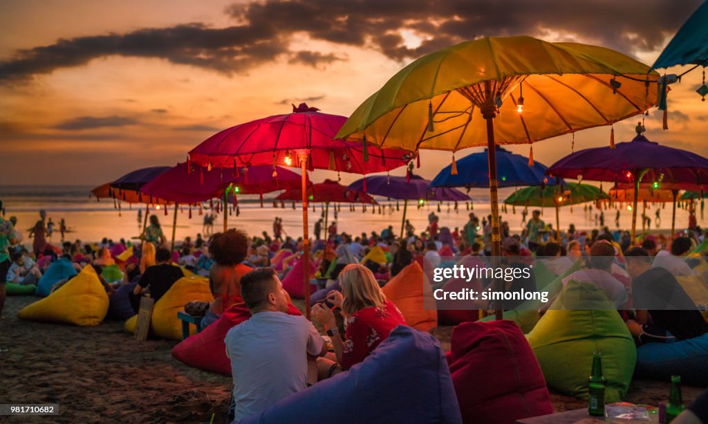 Crowded tourists relaxing on the beach at dusk in Bali, Indonesia