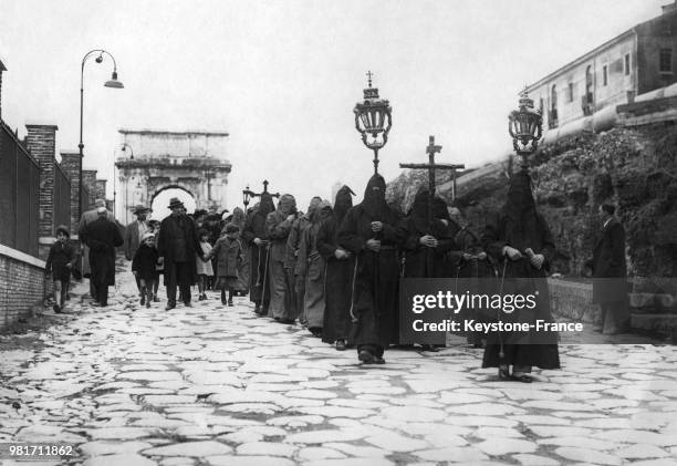 Procession des frères de la Miséricorde lors du chemin de croix en direction du Colisée à Rome en Italie - En arrière-plan, l'arc de Titus.