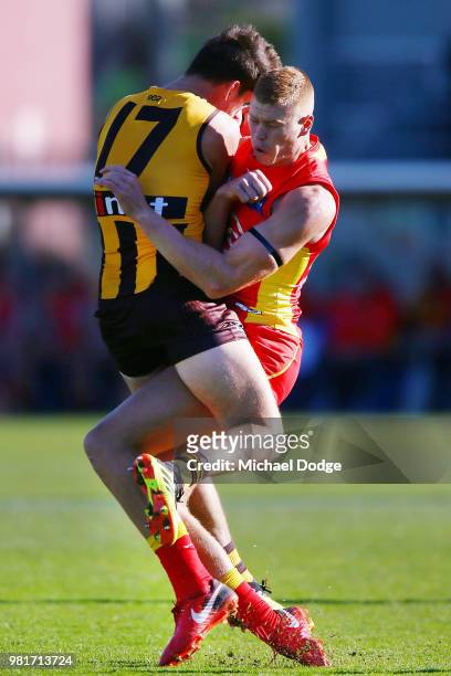 Daniel Howe of the Hawks marks the ball bravelt as he is crunched by Peter Wright of the Suns during the round 14 AFL match between the Hawthorn...