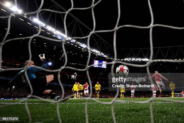 Goalkeeper Victor Valdes of Barcelona dives in vain as Cesc Fabregas of Arsenal scores a penalty to level the scores at 2-2 during the UEFA Champions...