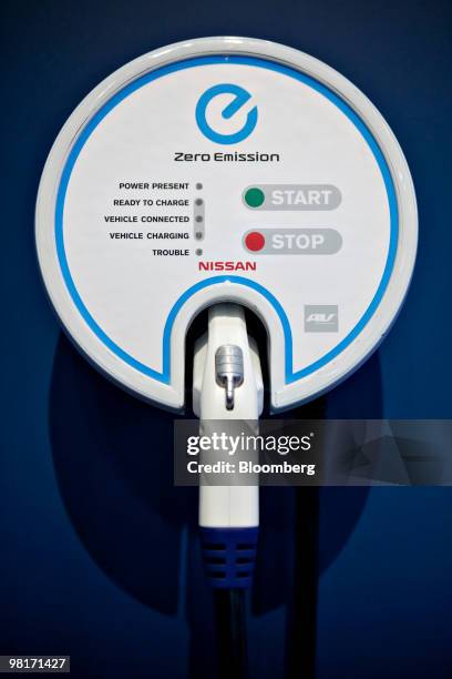 An electric charging station hangs near a Nissan Leaf electric vehicle on display during a media preview of the New York International Auto Show in...