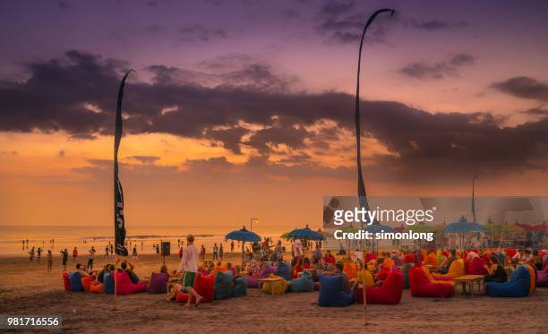 crowded beach at dusk in bali, indonesia - denpasar stock pictures, royalty-free photos & images