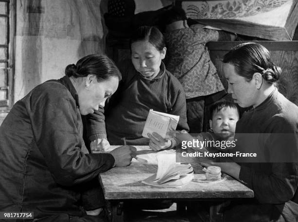 Tung Shu-ching, encore analphabète il y a 2 ans, apprend maintenant à lire et à écrire à deux femmes dans la province de Kirin en Chine, en mai 1958.