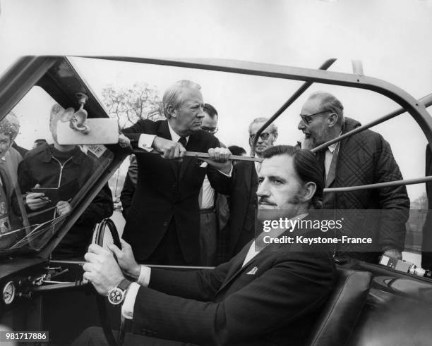 Graham Hill fait la démonstration d'une voiture adaptée aux conducteurs hémophiles au premier ministre Edward Heath à Bexleyheath en Angleterre au...