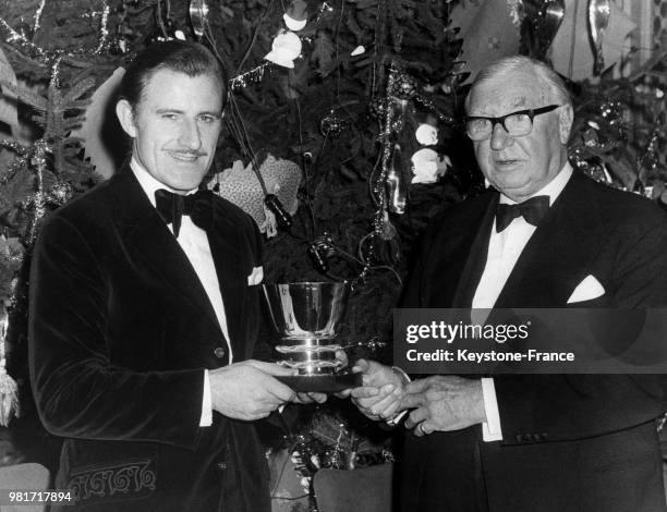 Graham Hill recevant le trophée de la Fédération Internationale de l'Automobile des mains du président du Royal Automobile Club Alfrid Andrews lors...