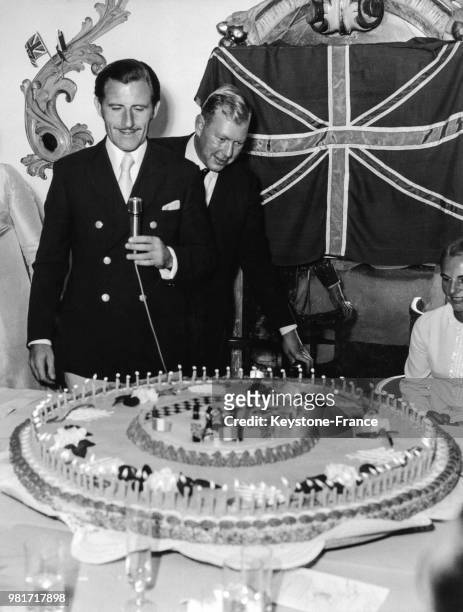 Graham Hill reçoit, de la part d'un groupe de journalistes spécialisés en sport automobile, un gâteau avec cent bougies, le nombre de courses qu'il a...