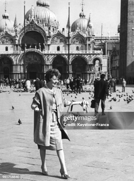 Edwige Feuillère se promenant sur la place Saint-Marc à Venise en Italie, circa 1960 - En arrière-plan, la basilique Saint-Marc.