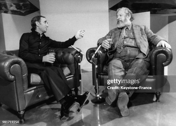 Charles Aznavour et Peter Ustinov, un verre de whisky à la main, discutent sur le plateau de l'émission télévisée 'Numéro Un', à Paris, France, le 19...