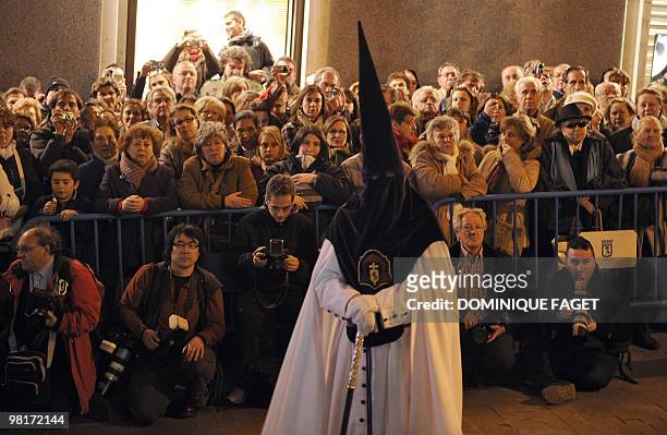 Photographers and people gather as they wait as a penitent stands in front of them before the ''Nuestro Padre Jesus de la Salud" brotherhood...