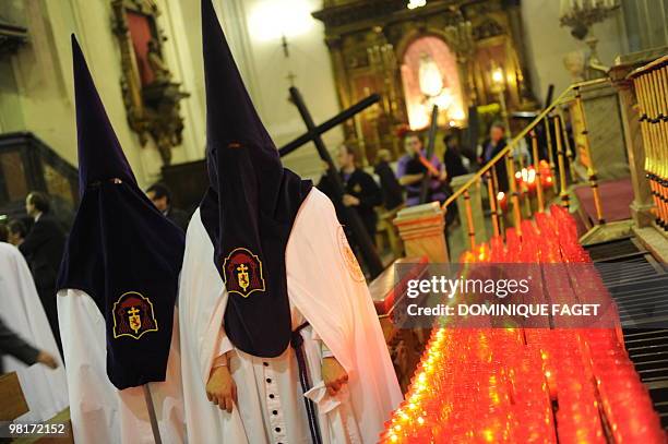 Two penitents walk past candles as they take part in the ''Nuestro Padre Jesus de la Salud" brotherhood procession during the Holy Week in Madrid on...