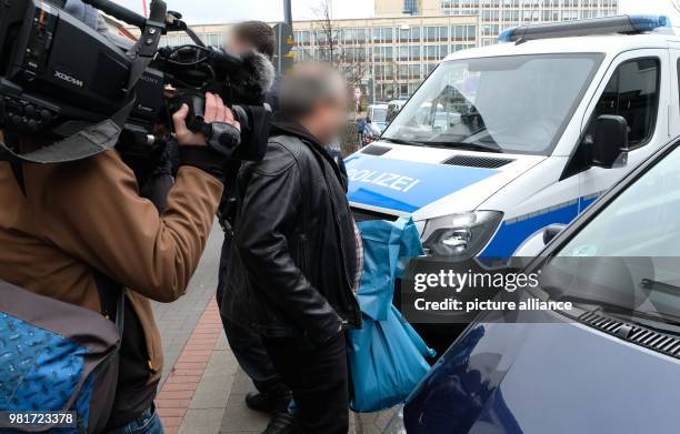 April 2018, Germany, Hannover: Two police officers in civil clothing carrying boxes of confiscated documents to a car during a raid of the Kurdish...