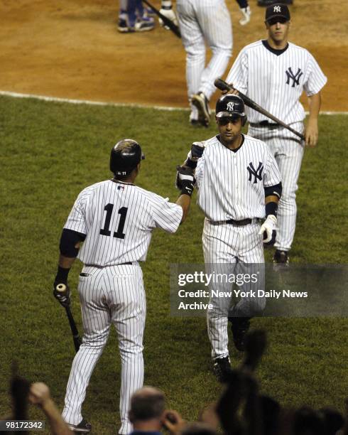 Derek Jeter of the New York Yankees is greeted by teammate Gary Sheffield after he hit a home run in the 4th inning against the Texas Rangers on...