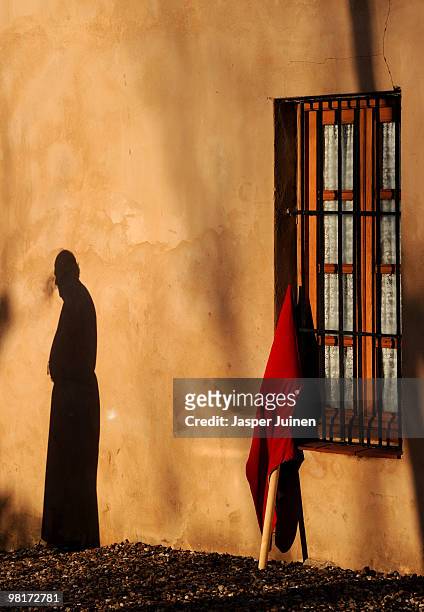 Penitent of the Cofradia del Silencio casts his shadow on a wall next to his hood as he prepares for a Holy Week procession on March 31, 2010 in...