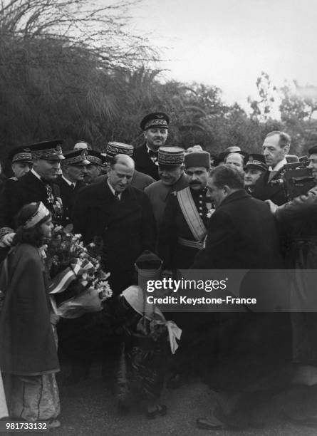 Deux fillettes offrent des bouquets de fleurs au président du conseil Edouard Daladier à Bizerte en Tunisie, le 4 janvier 1939.