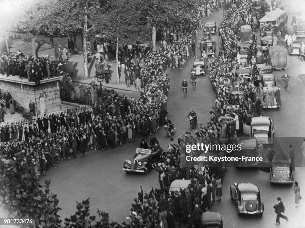 Devant l'église de la Madeleine, la foule acclame le président du conseil Edouard Daladier, de retour de Munich, debout dans la voiture qui le...