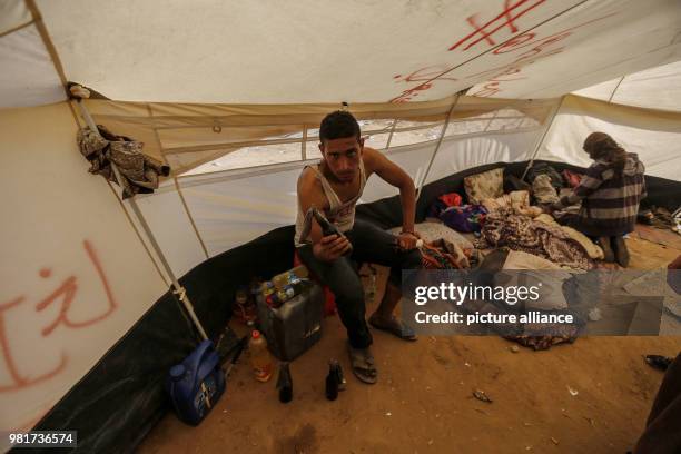 Dpatop - A Palestinian man holds up a Molotov cocktail inside a tent during a tent city protest along the Israel-Gaza border, demanding the right to...