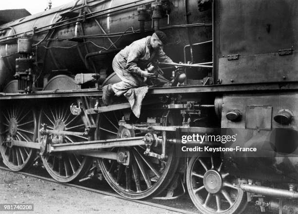 Graissage des roues, pistons et bielles d'une locomotive à vapeur de la compagnie du chemin de fer Paris-Lyon-Méditerranée , en France, en 1938.