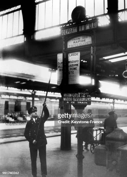 Employé de la compagnie du chemin de fer Paris-Lyon-Méditerranée changeant un panneau de départ de train sur le quai d'une gare en France, en...