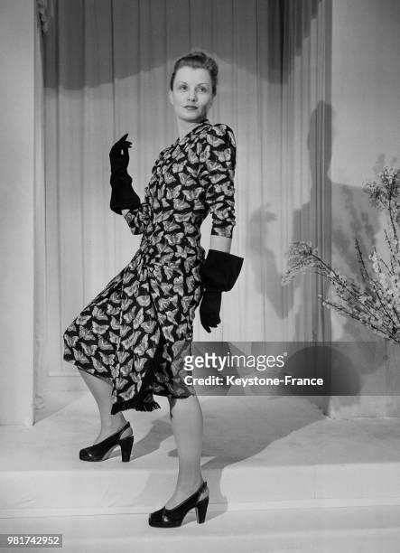 Mannequin présentant 'Les papillons' de Maggy Rouff : une robe de crêpe noire et impressions claires, drapées aux hanches, le 19 février 1947.