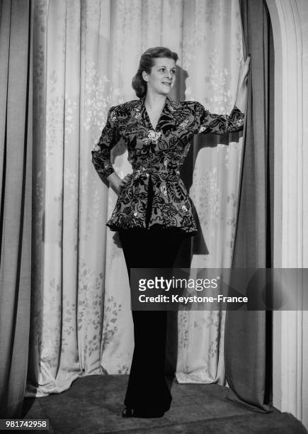 Mannequin présentant un modèle de Jacques Costet : une jupe longue et étroite de teinte sombre agrémentée d'une tunique imprimée fleurie à basque, le...