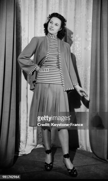 Mannequin présentant un tailleur de lainage composé d'une jupe plissée et d'une veste longue, en 1947.
