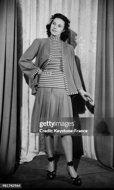 Mannequin présentant un tailleur de lainage composé d'une jupe plissée et d'une veste longue, en 1947.