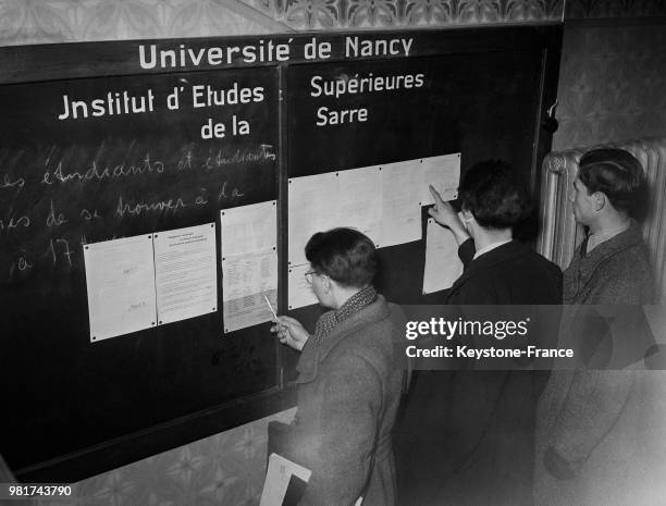 Etudiants consultant un tableau à l'institut d'études supérieures de la Sarre dans le hall de l'université de Nancy en France, le 26 mars 1947.