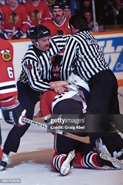 Linesman Swede Knox and linesman Dan McCourt try to break up a fight between John Kordic of the Toronto Maple Leafs and Cam Russell of the Chicago...