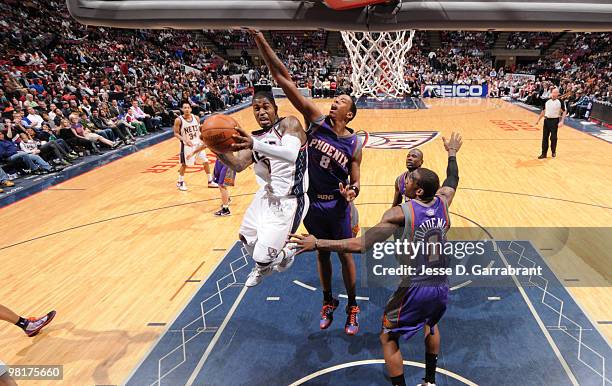 Terrence Williams of the New Jersey Nets shoots against Channing Frye and Amar'e Stoudemire of the Phoenix Suns during the game on March 31, 2010 at...