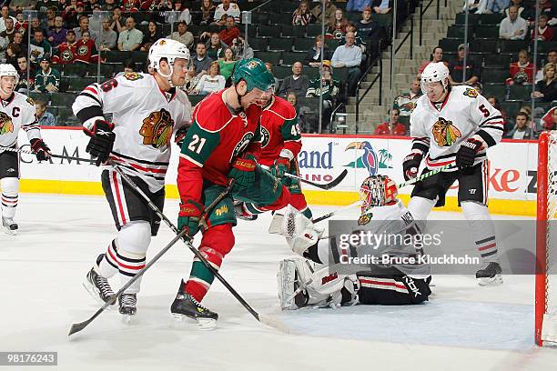 Kyle Brodziak of the Minnesota Wild is stopped on a scoring attempt by goalie Antti Niemi and Dave Bolland of the Chicago Blackhawks during the game...