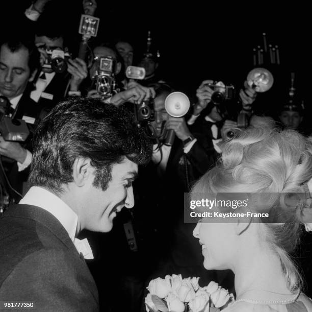 Jean-Claude Brialy accueille Brigitte Bardot à son arrivée au gala de l'union des artistes à l'opéra Garnier à Paris en France, le 18 mars 1966.