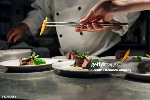 professional chef at work in a busy kitchen getting ready for service - gourmet stock pictures, royalty-free photos & images