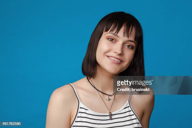 close-up portrait einer jungen attraktiven 18 jährige frau in sommerkleidung in einem studio auf blauem hintergrund - girl close up stock-fotos und bilder